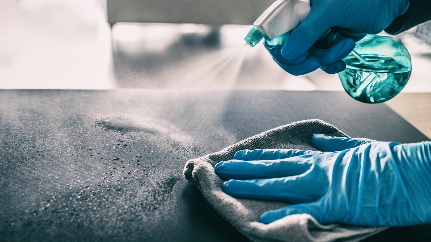 A person in blue gloves is cleaning a table